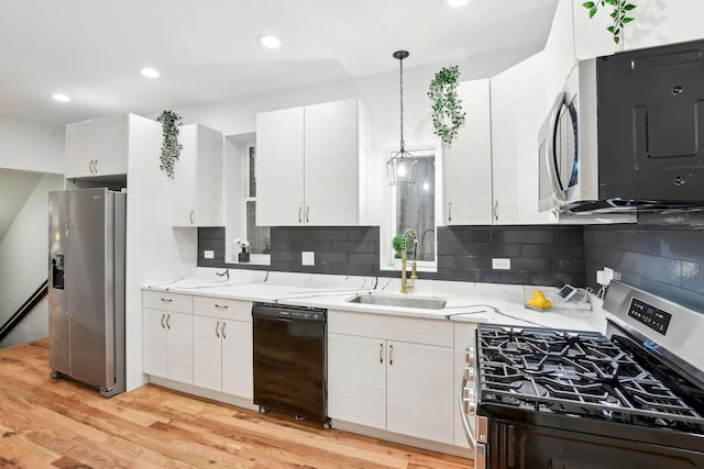 kitchen featuring backsplash, light wood-style flooring, stainless steel appliances, and a sink