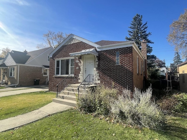 bungalow with brick siding, a chimney, and a front yard