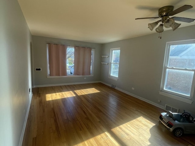 spare room featuring baseboards, visible vents, and wood finished floors