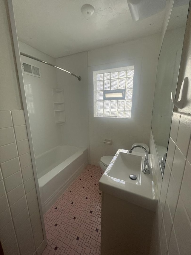 bathroom featuring tile walls, visible vents, toilet, tub / shower combination, and vanity