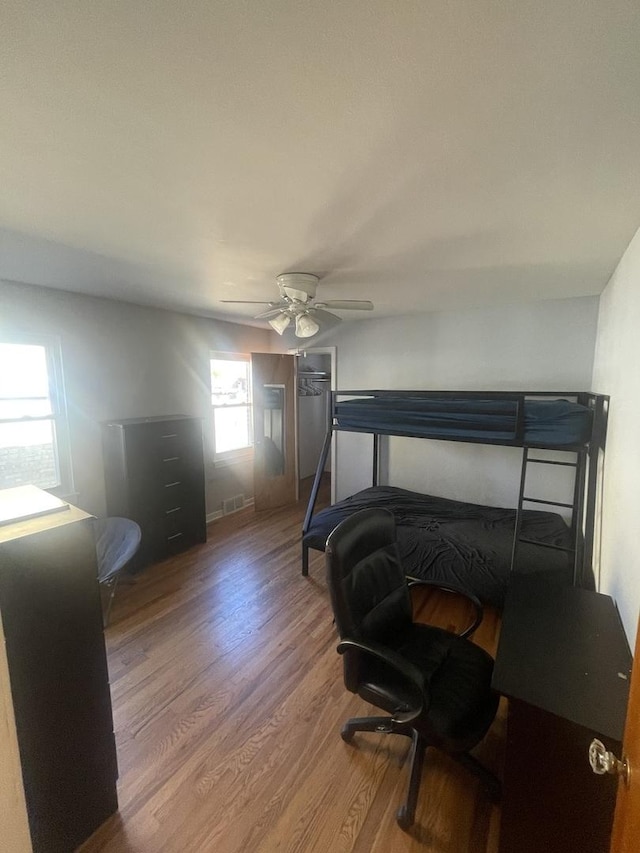 bedroom with ceiling fan, wood finished floors, and visible vents