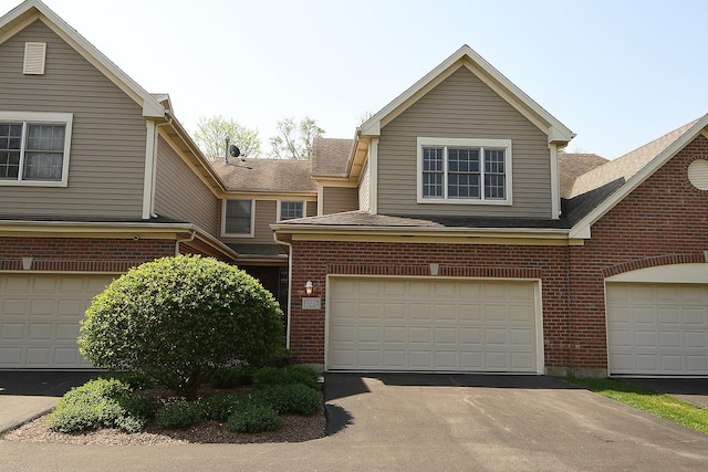 traditional home featuring a garage, aphalt driveway, and brick siding