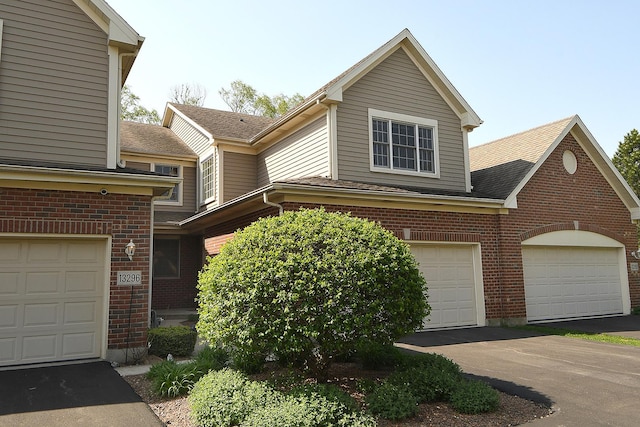 view of front of property with aphalt driveway, a shingled roof, and brick siding