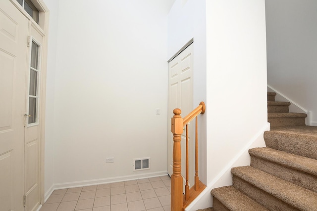 staircase featuring baseboards, visible vents, and tile patterned floors