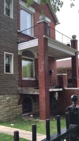 view of property exterior with brick siding and a balcony