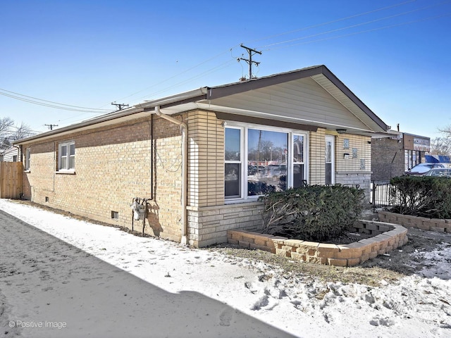 view of front of property featuring crawl space, brick siding, and fence