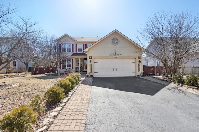 traditional-style house featuring an attached garage, fence, and aphalt driveway