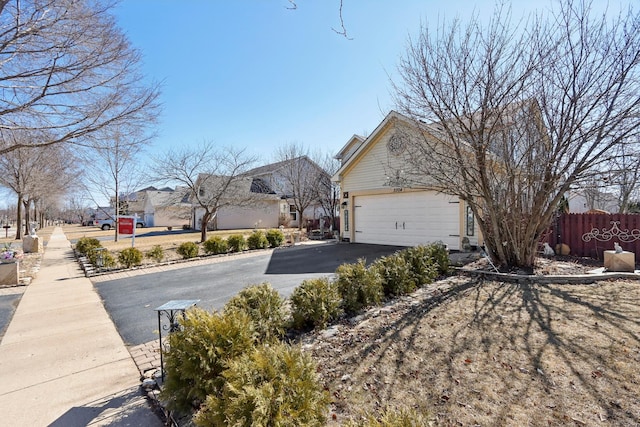 view of side of home featuring a garage, fence, and aphalt driveway