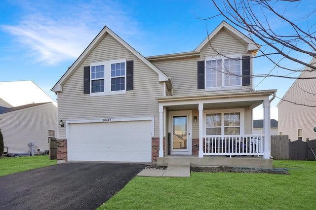 traditional-style house with a garage, a front yard, covered porch, and driveway