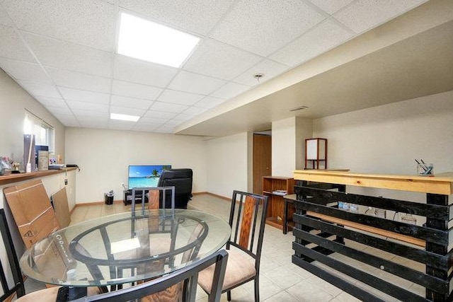 dining room with light tile patterned flooring, a paneled ceiling, and baseboards