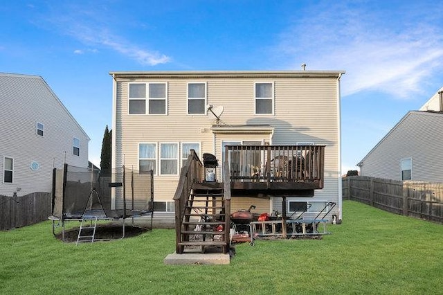 rear view of property featuring a deck, a yard, stairway, and a trampoline