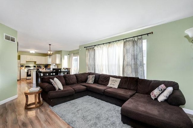 living room featuring visible vents, baseboards, and wood finished floors