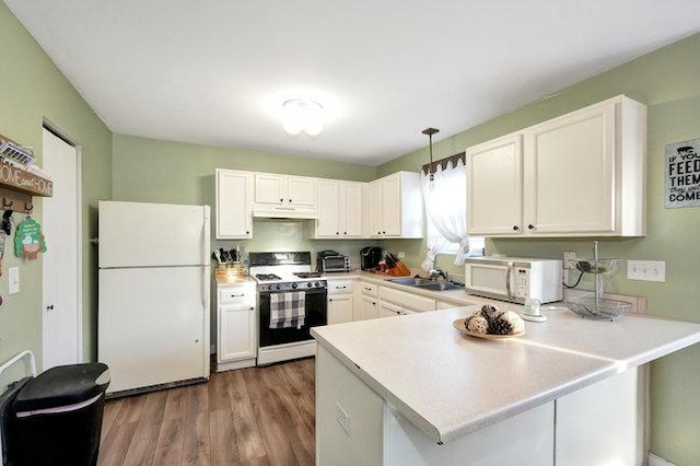 kitchen featuring a peninsula, white appliances, white cabinets, and under cabinet range hood