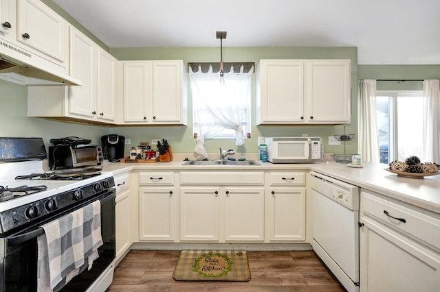 kitchen featuring white appliances, white cabinets, light wood-style flooring, under cabinet range hood, and a sink