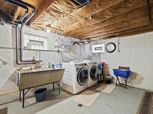 clothes washing area with laundry area, a sink, and washing machine and clothes dryer