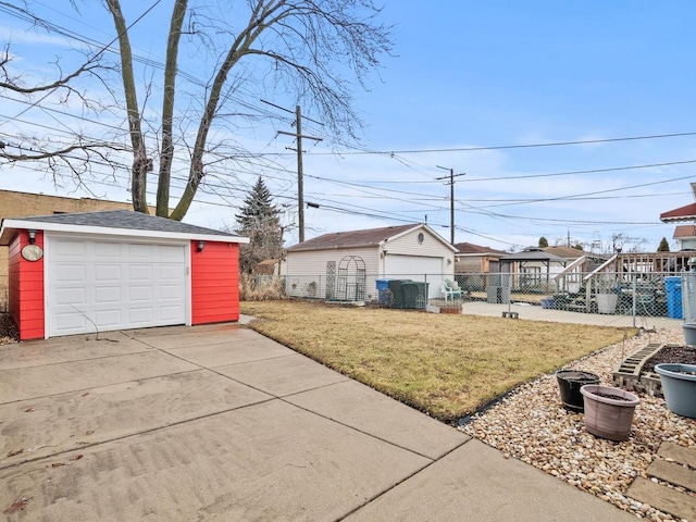 view of yard with a garage, an outbuilding, and fence