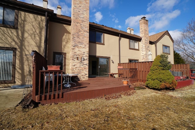 rear view of property with a chimney and a deck