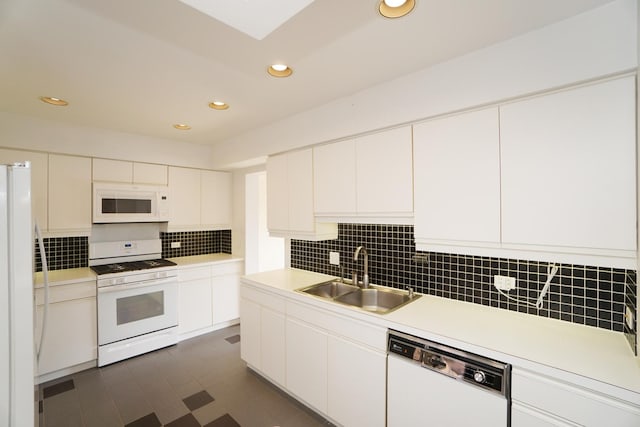 kitchen featuring white appliances, a sink, white cabinets, light countertops, and tasteful backsplash