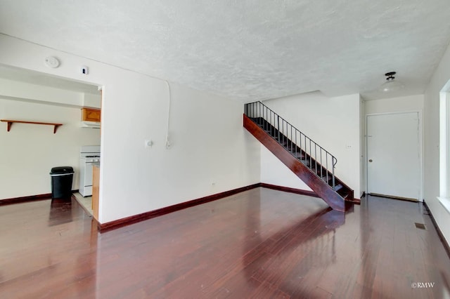 unfurnished living room featuring visible vents, baseboards, wood finished floors, stairs, and a textured ceiling