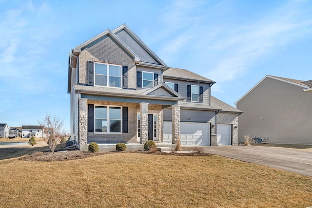 733 Juniper St, Oswego, IL 60543 - craftsman inspired home with asphalt driveway, a front lawn, an attached garage, a porch, and stone siding