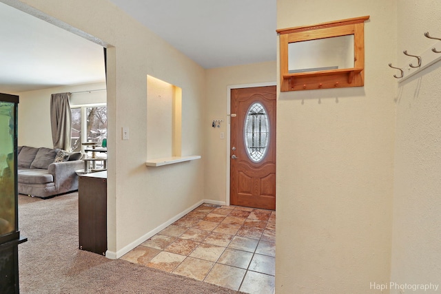 foyer entrance featuring baseboards and light colored carpet