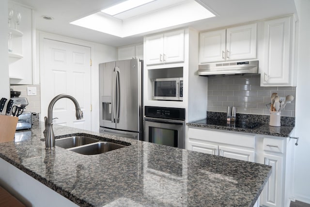 kitchen featuring white cabinets, a peninsula, stainless steel appliances, under cabinet range hood, and a sink