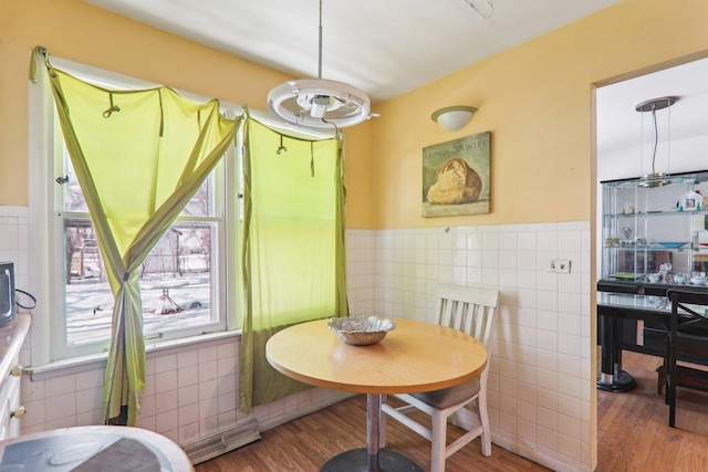 dining area featuring a wainscoted wall, wood finished floors, and tile walls