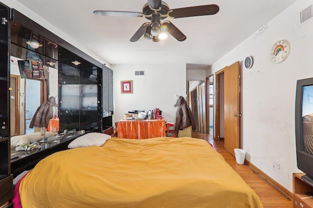 bedroom featuring a ceiling fan, baseboards, visible vents, and light wood finished floors