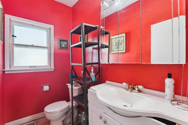 bathroom featuring baseboards, vanity, and toilet