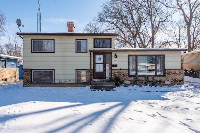 split level home featuring brick siding and a chimney