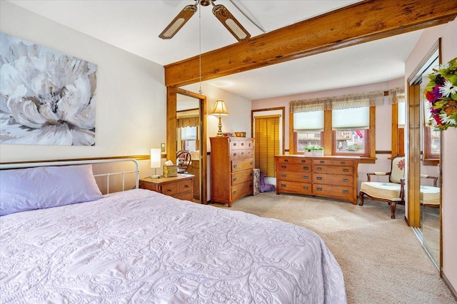 carpeted bedroom with ceiling fan and beam ceiling