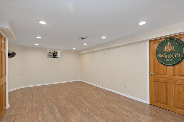 finished basement featuring recessed lighting, visible vents, light wood-style flooring, and baseboards