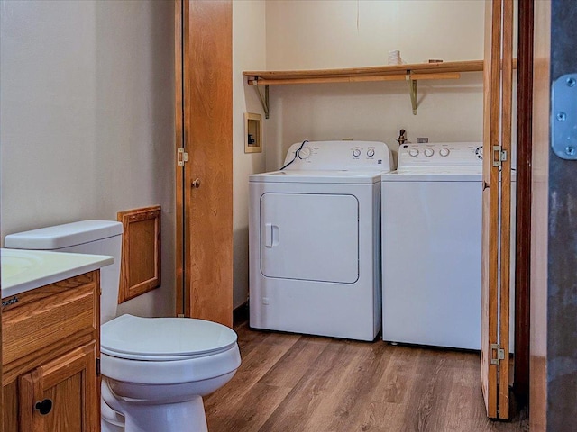 laundry area with laundry area, wood finished floors, and washing machine and clothes dryer