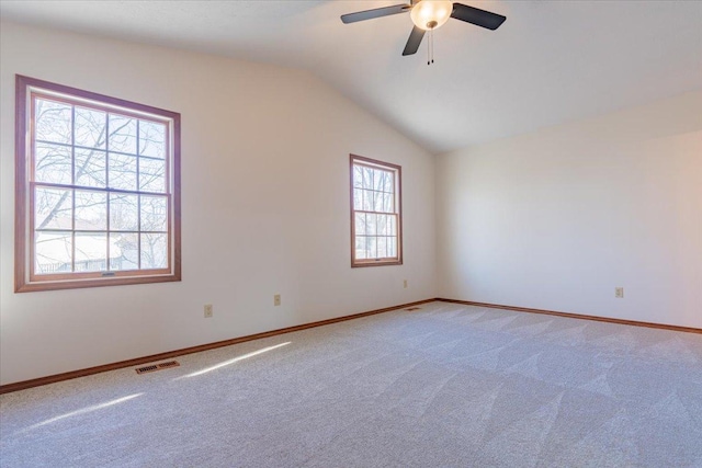 empty room with lofted ceiling, ceiling fan, light carpet, visible vents, and baseboards