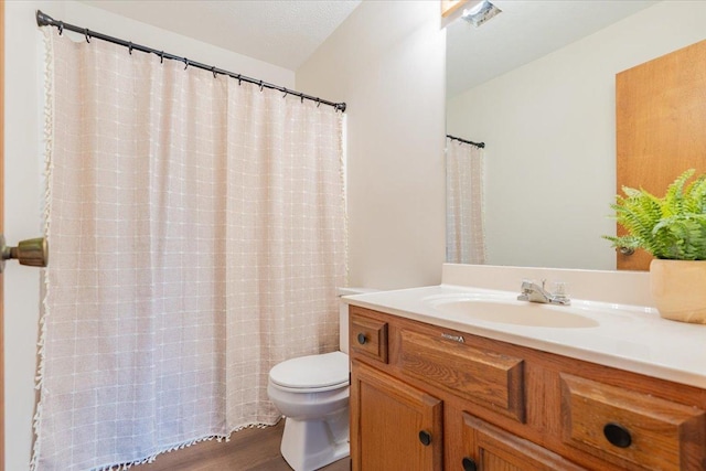 bathroom with a shower with shower curtain, toilet, wood finished floors, a textured ceiling, and vanity