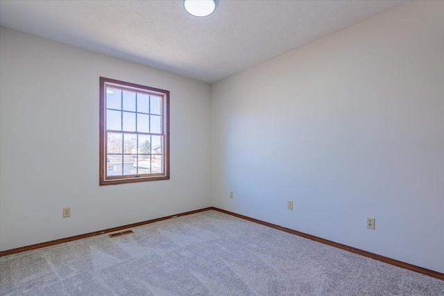 carpeted empty room with baseboards, visible vents, and a textured ceiling