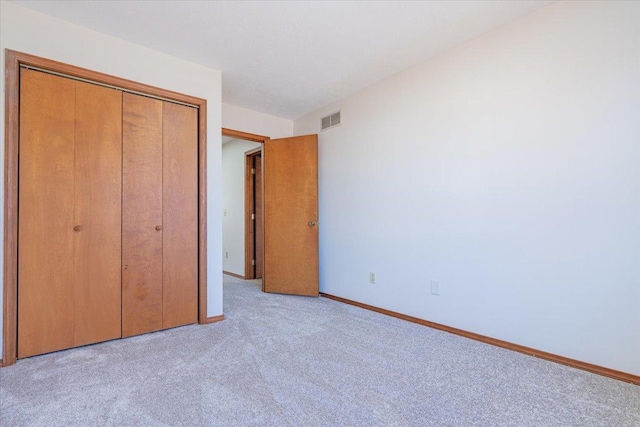 unfurnished bedroom featuring light carpet, baseboards, visible vents, and a closet