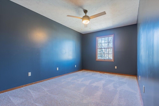 spare room with carpet, ceiling fan, a textured ceiling, and baseboards