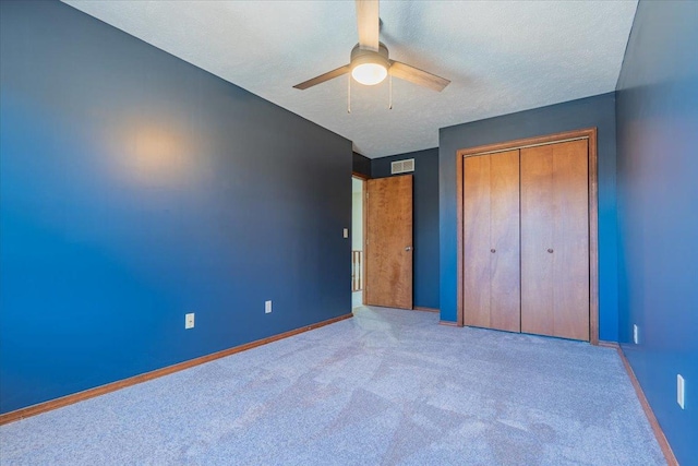 unfurnished bedroom featuring visible vents, baseboards, a textured ceiling, carpet floors, and a closet