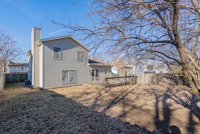 rear view of property with a fenced backyard, a chimney, a wooden deck, and central air condition unit