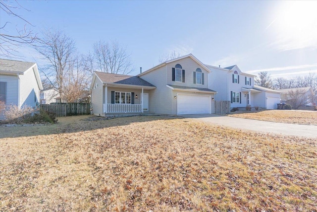 traditional-style home with a garage, concrete driveway, covered porch, and fence