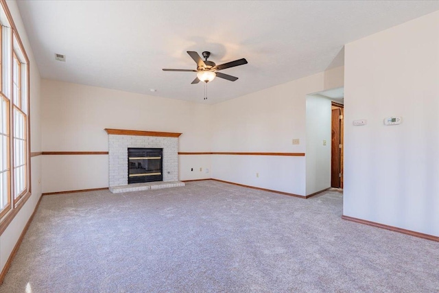 unfurnished living room featuring carpet, a fireplace, visible vents, a ceiling fan, and baseboards