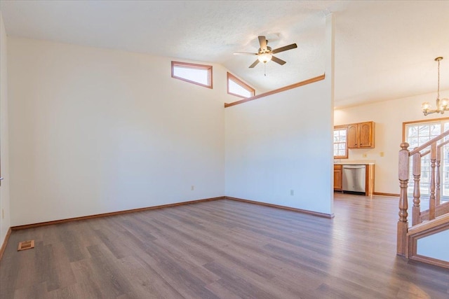 spare room with stairway, wood finished floors, high vaulted ceiling, baseboards, and ceiling fan with notable chandelier