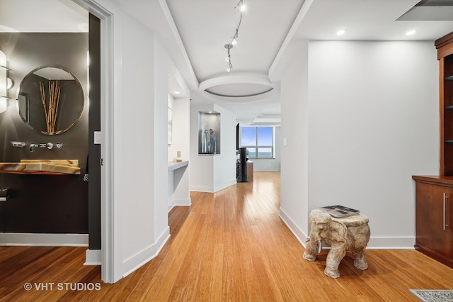 corridor featuring rail lighting, baseboards, wood finished floors, and recessed lighting