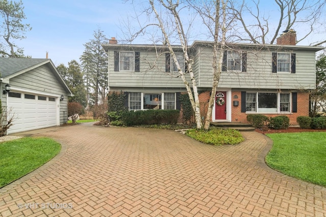 colonial home with brick siding, a front lawn, a chimney, and decorative driveway