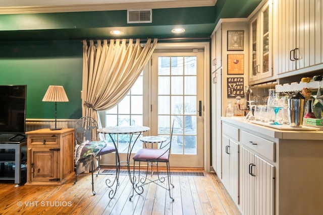 interior space with crown molding, light wood finished floors, and visible vents