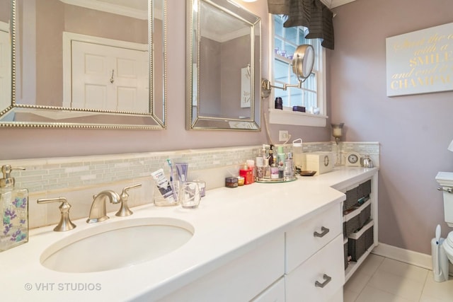 bathroom with tile patterned flooring, toilet, vanity, baseboards, and decorative backsplash