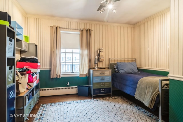 bedroom featuring baseboard heating, wood finished floors, ceiling fan, and crown molding