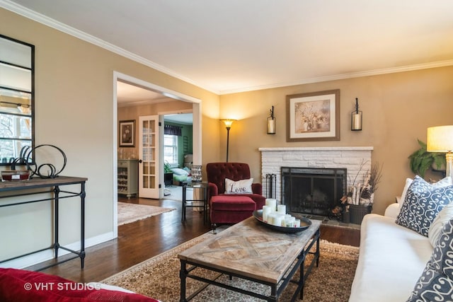 living area with crown molding, a stone fireplace, and wood finished floors