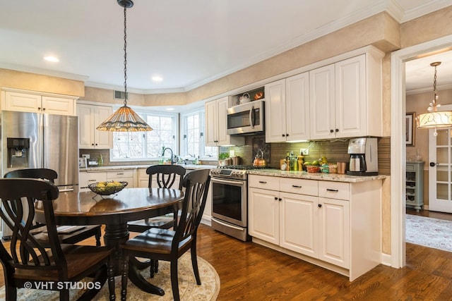 kitchen featuring hanging light fixtures, crown molding, stainless steel appliances, and dark wood-type flooring